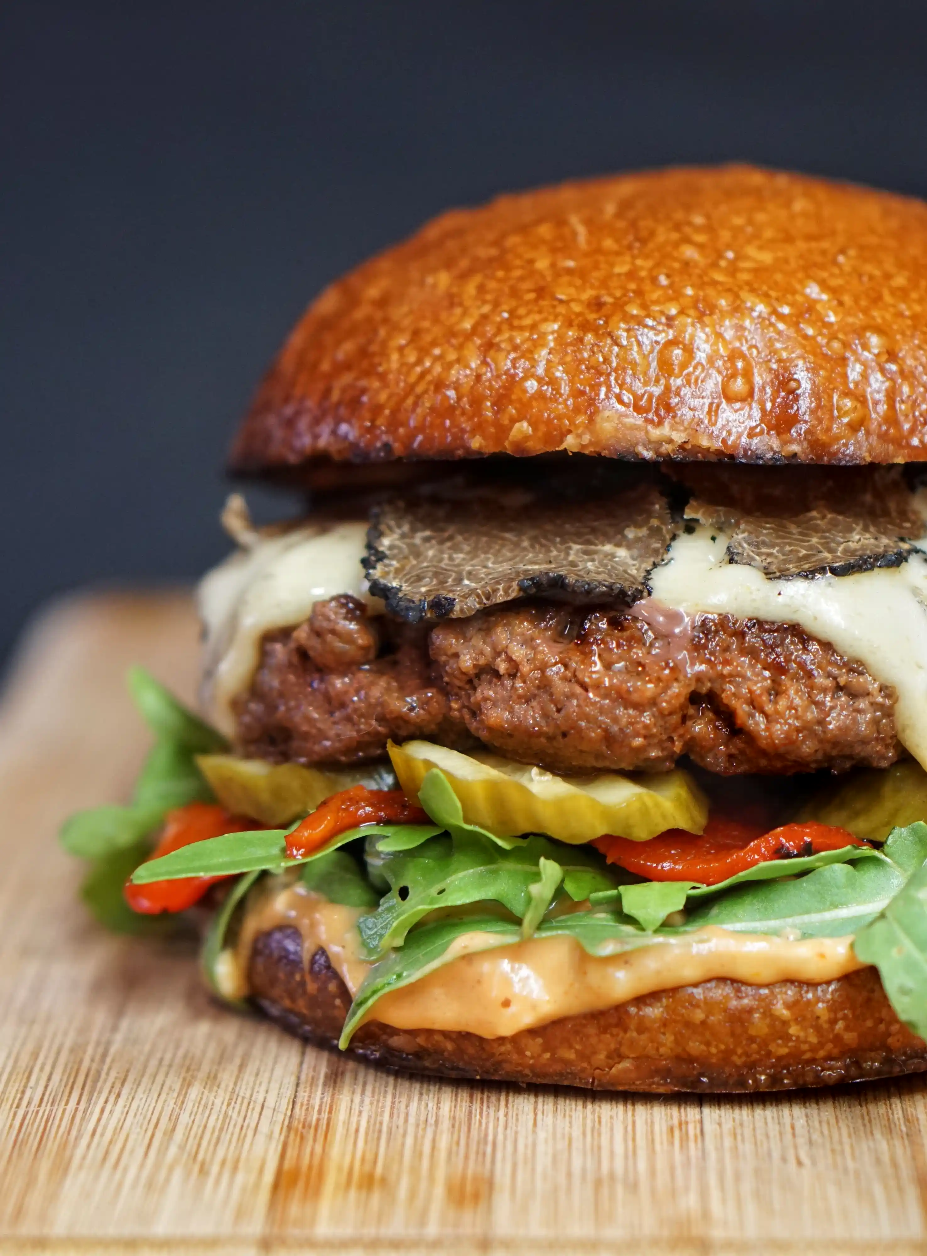 Hamburger with lettuce, cheese and pickles on a cutting board